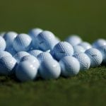 vita golfbollar i en hög på en grön gräsmatta