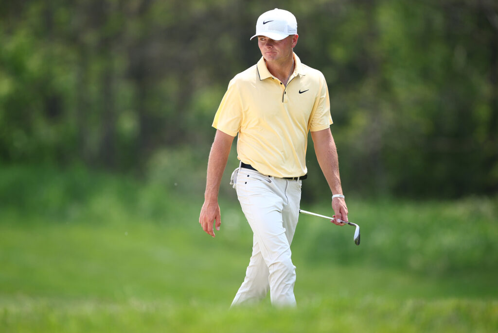 golfspelaren luke clanton går på en grön golfbana iklädd en gul pikétröja