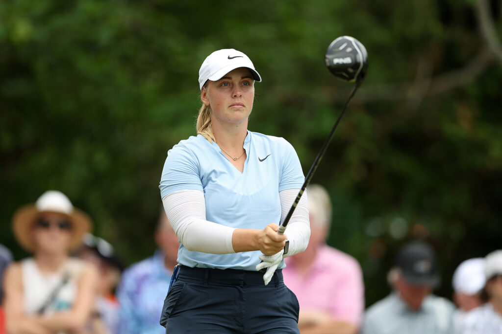 golfspelaren maja stark med en ping-driver på en golfbana. har en turkos piké på sig