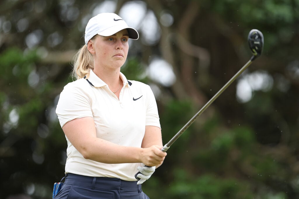 golfspelaren maja stark i rosa piké hållandes i en hybrid.