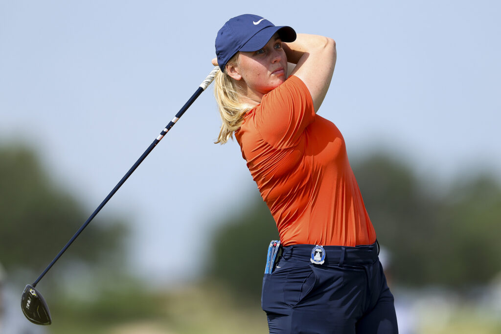 golfspelaren maja stark i en röd piké hållandes i en svart driver