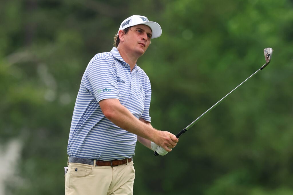 golfspelaren henrik norlander med en järnklubba, vit golfkeps och blå golfpiké