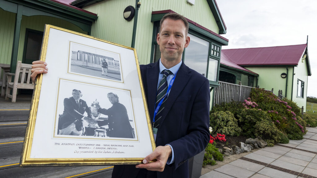 I klubbuset på Royal Portcrawl hänger det bilder från tidigare svenska segrare på Royal Portcrawl här håller Managern för Royal Portcrawl John Edwards upp tavlan med Christian "Kricken" Härdin och hans seger i British Am 1988