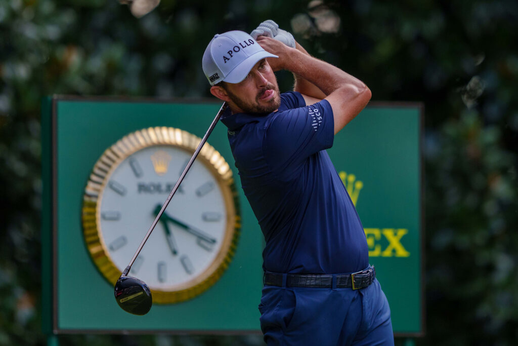 golfspelaren patrick cantlay framför en stor rolexklocka på en golfbana