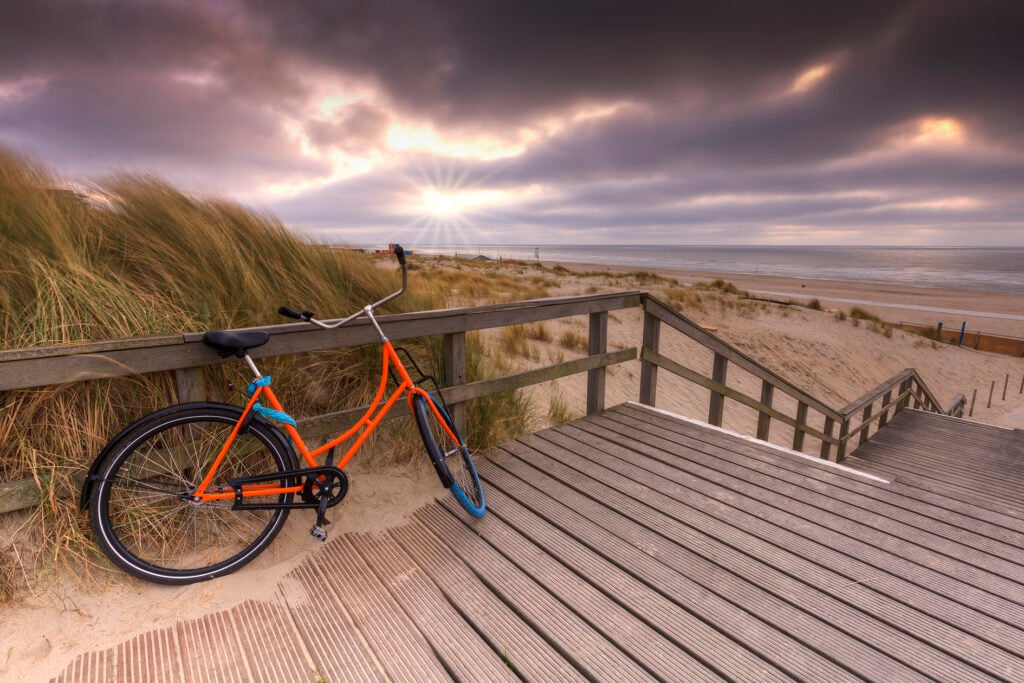 orange cykel på strand i nederländerna