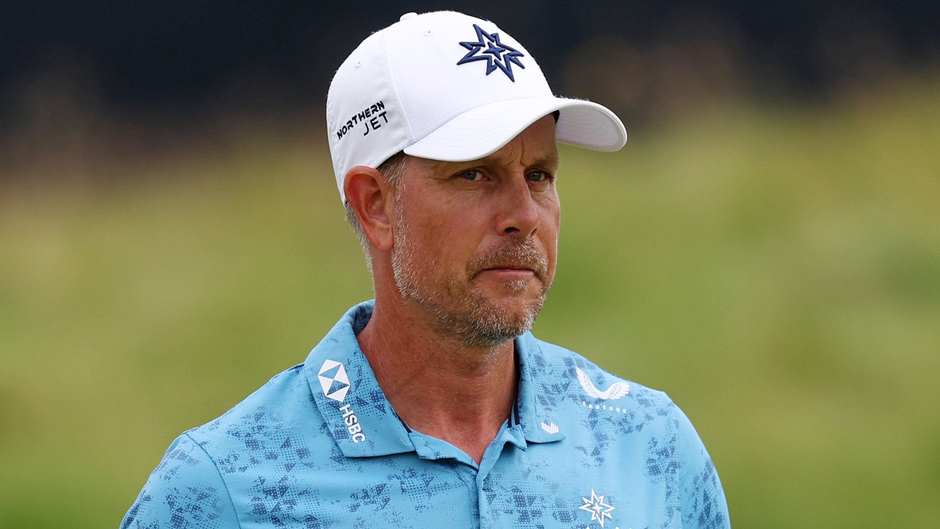 golfspelaren henrik stenson i vit golfkeps och blå, mönstrad golfpiké