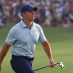 golfspelaren rory mcilroy i ljusblå golfpiké och mörk golfkeps och golfbyxor på en grön golfbana