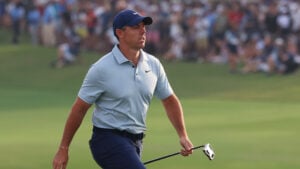 golfspelaren rory mcilroy i ljusblå golfpiké och mörk golfkeps och golfbyxor på en grön golfbana