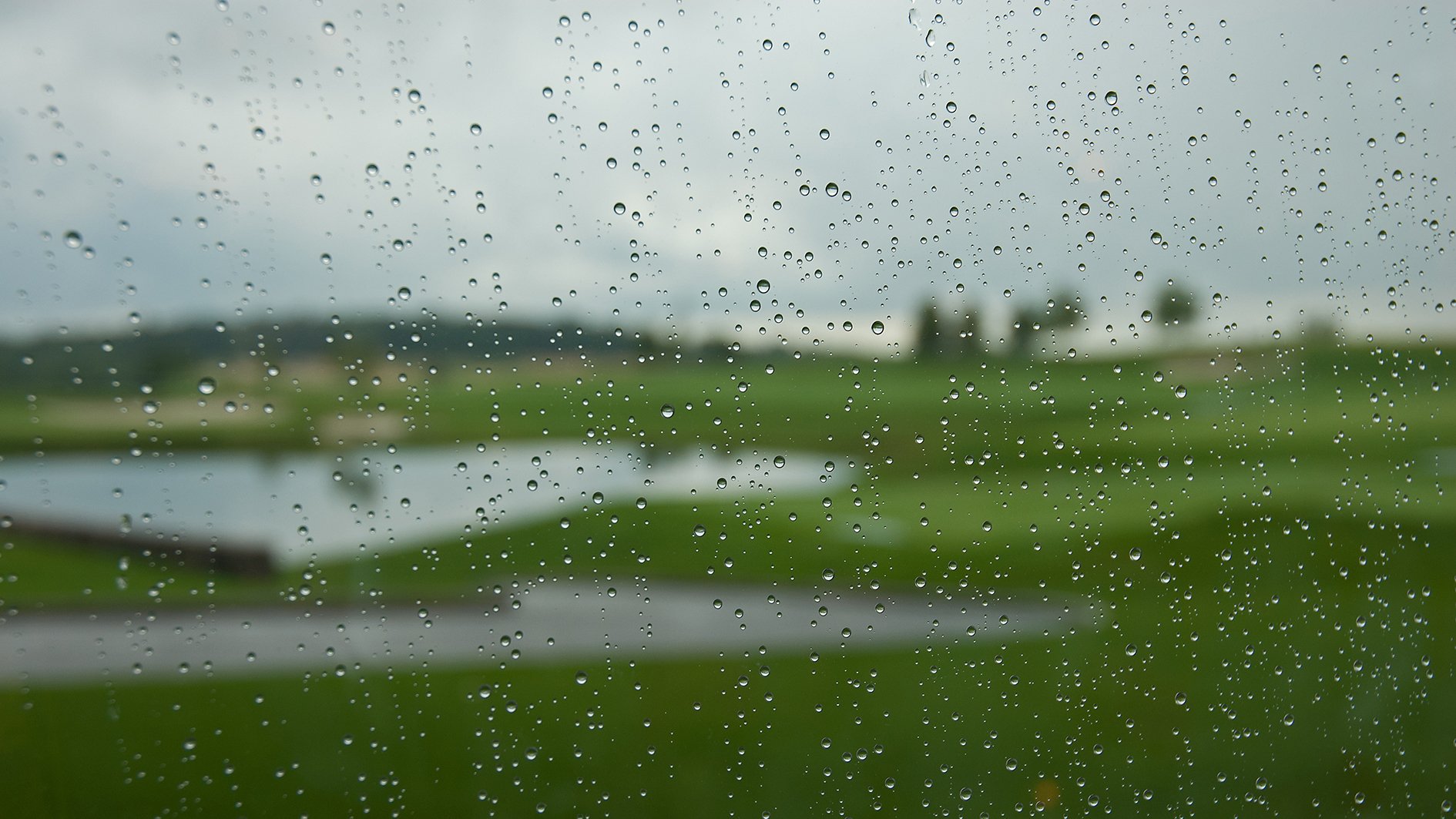 regndroppar på ruta ut mot golfbana