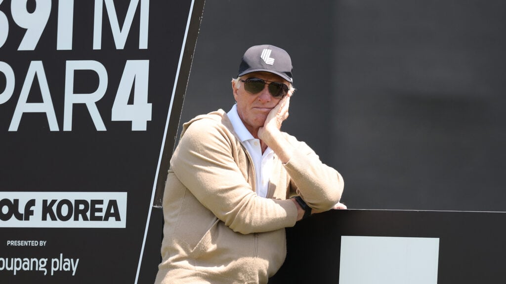 golfspelaren greg norman i solglasögon lutande mot en svart skylt med vit text