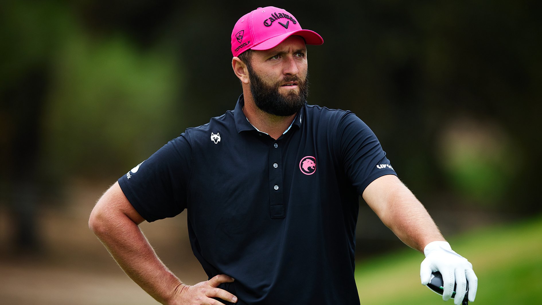 golfspelaren jon rahm i rosa golfkeps och svart golfpiké