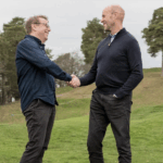 två män skakar hand på en golfbana