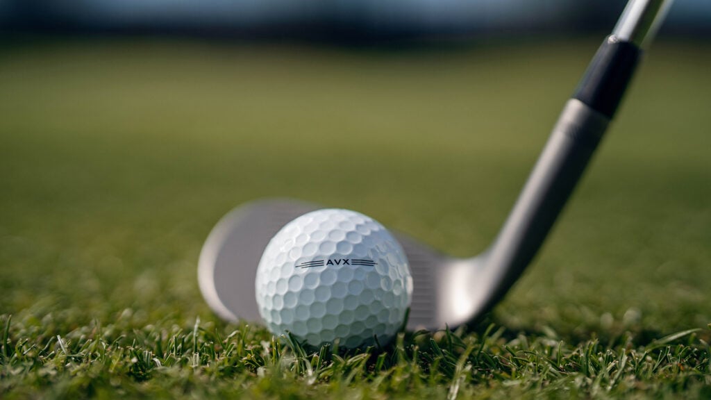 vit golfboll och golfklubba med hög loft på grönt gräs