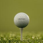 vit golfboll på vit golfpeg i grönt gräs