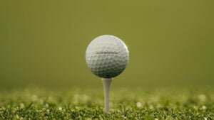 vit golfboll på vit golfpeg i grönt gräs