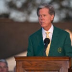 augusta national golf clubs och the masters ordförande Fred Ridley vid ett podium i trä iklädd grön kavaj