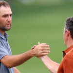 golfspelarna scottie scheffler och rory mcilroy skakar hand på en grön golfbana