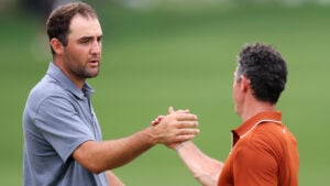 golfspelarna scottie scheffler och rory mcilroy skakar hand på en grön golfbana