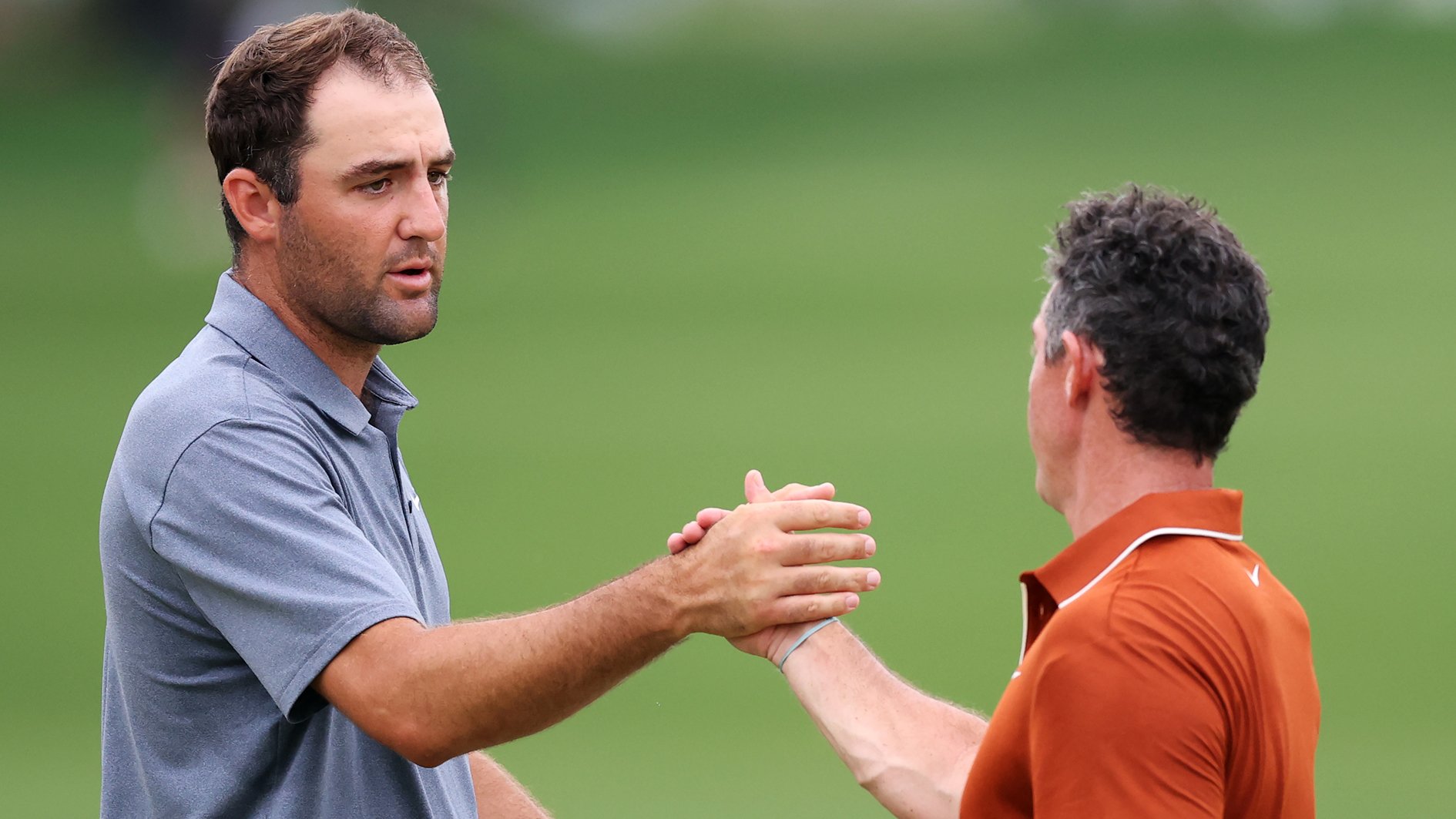 golfspelarna scottie scheffler och rory mcilroy skakar hand på en grön golfbana