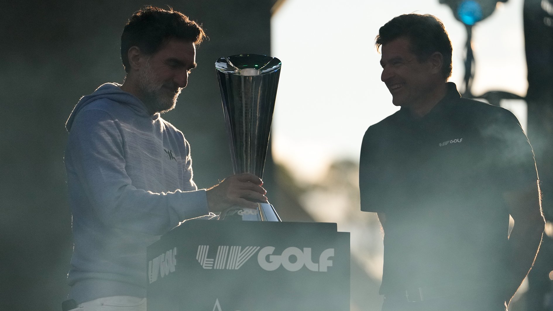 två män vid ett podium och en pokal