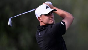 golfspelaren ludvig åberg med en järnklubba, vit golfkeps och svart golfpiké