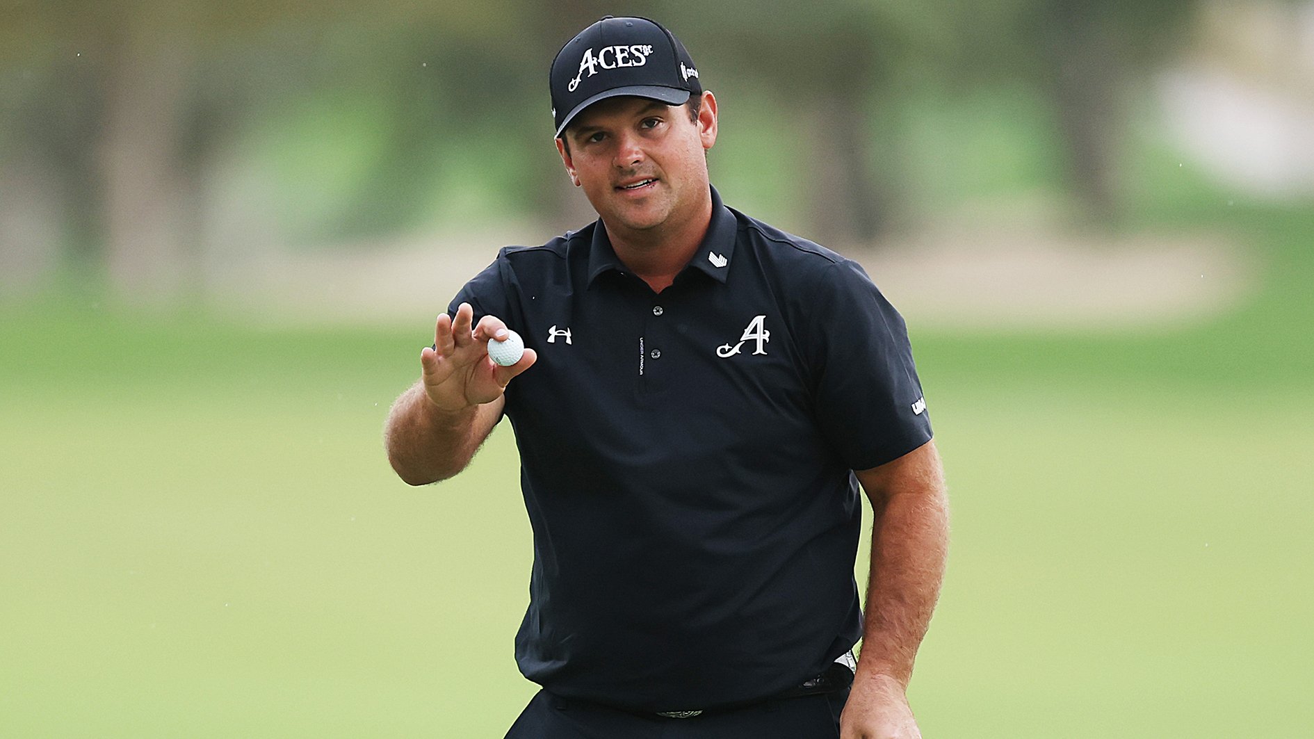 golfspelaren patrick reed i svarta golfkläder på grön golfbana