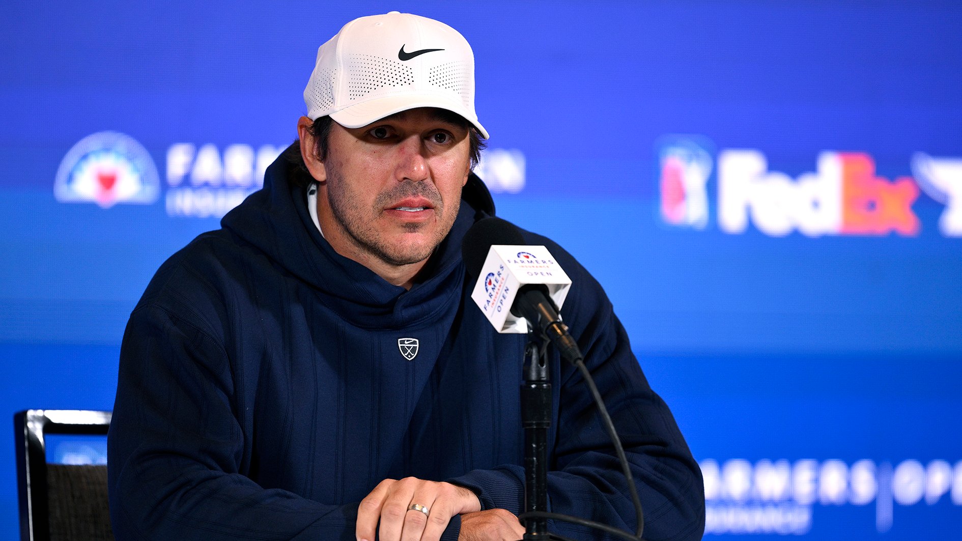 golfspelaren brooks koepka i vit golfkeps och svart luvtröja