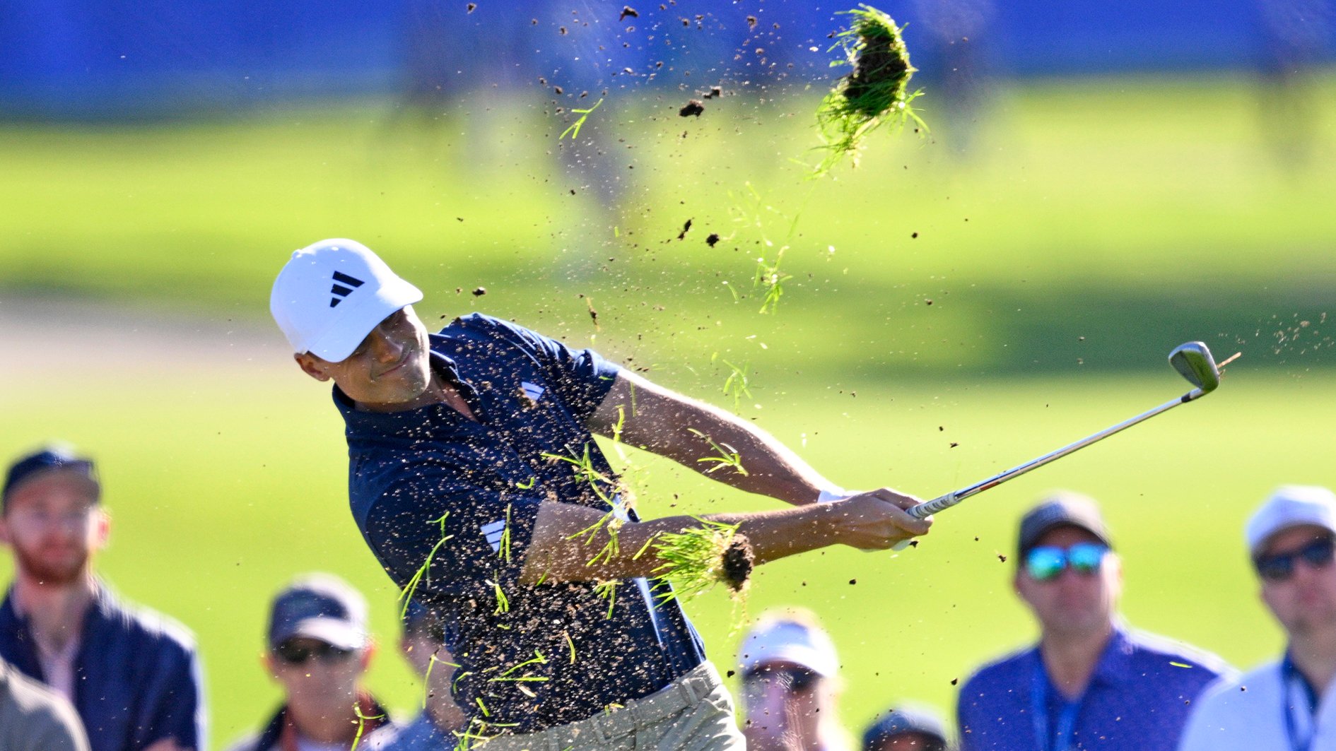 golfspelaren ludvig åberg slår upp gräs på en golfbana