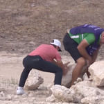 golfspelaren joakim lagergren och caddien jesse karlsson flyttar stenblock på en golfbana