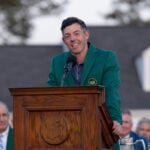 golfspelaren rory mcilroy i grön kavaj vid ett podium