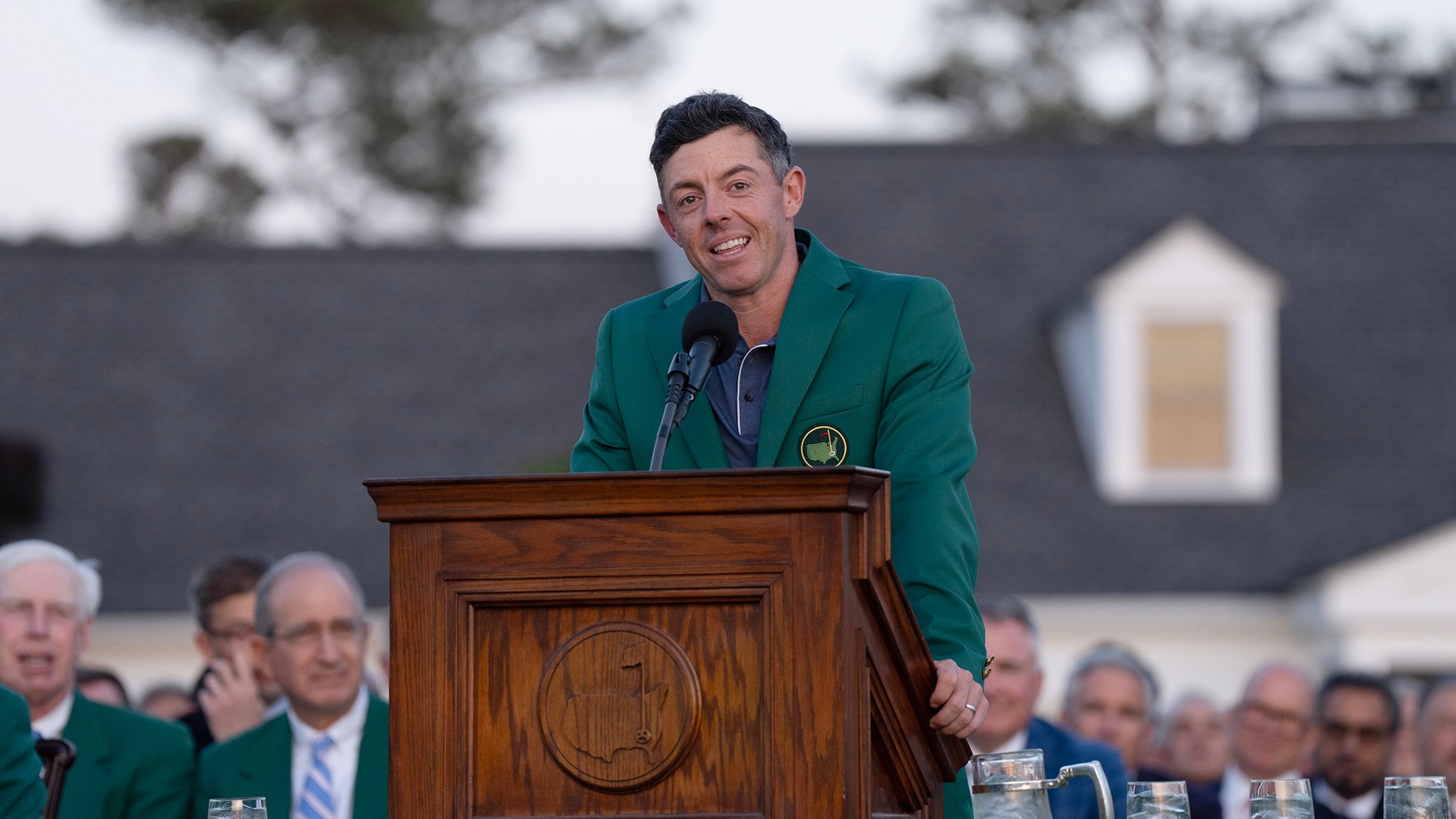 golfspelaren rory mcilroy i grön kavaj vid ett podium