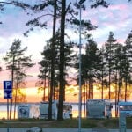 husbilar vid träd och sjö i solnedgång