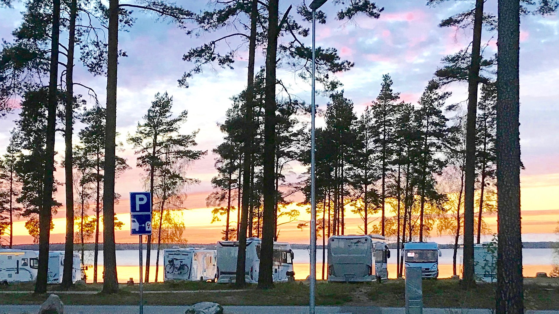 husbilar vid träd och sjö i solnedgång