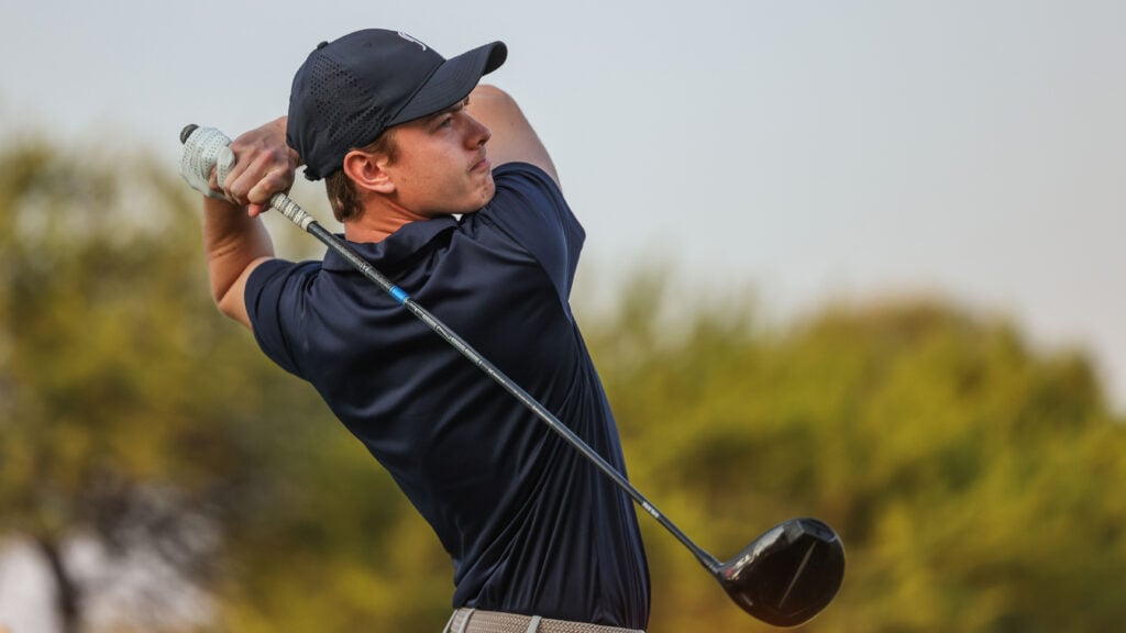 golfspelare slår med en golfklubba på en golfbana