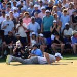 golfspelare, golfgreen, man på mage på gräs, publik, kameror,