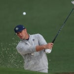 golfspelaren bryson dechambeau slår ett bunkerslag så sand flyger ur bunkern på en golfbana