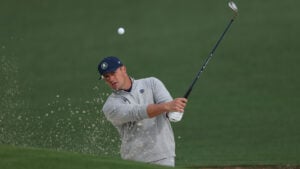 golfspelaren bryson dechambeau slår ett bunkerslag så sand flyger ur bunkern på en golfbana
