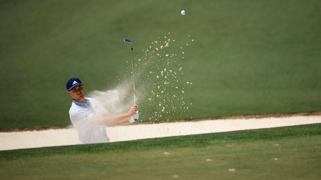 golfspelaren ludvig åberg slår ett bunkerslag på en golfbana så att sanden stänker