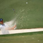 golfspelaren ludvig åberg slår ett bunkerslag på en golfbana så att sanden stänker