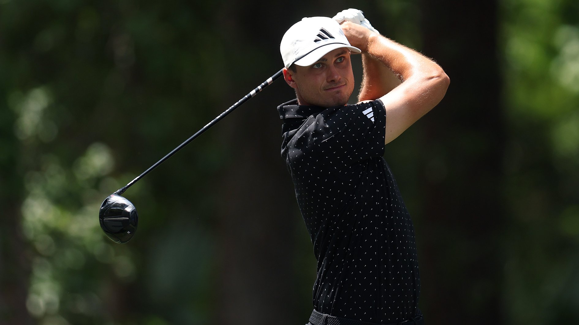 golfspelaren ludvig åberg iklädd svarta golfkläder svingar en driver på en golfbana