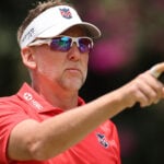 golfspelare i vit skärmkeps och solglasögon pekar med pekfingret