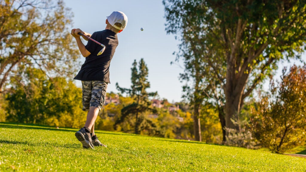 ung golfspelare på golfbana med golfklubba