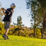 ung golfspelare på golfbana med golfklubba