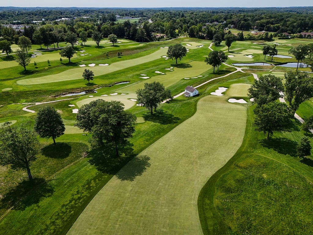 golfbana, träd, sandbunkrar, stenhus, vattendrag