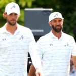 två golfspelare i vita golfkläder på en golfbana