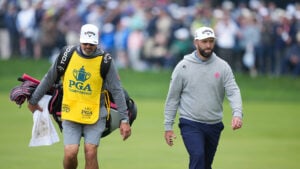 golfspelare och caddie på golfbana under golftävling med publik