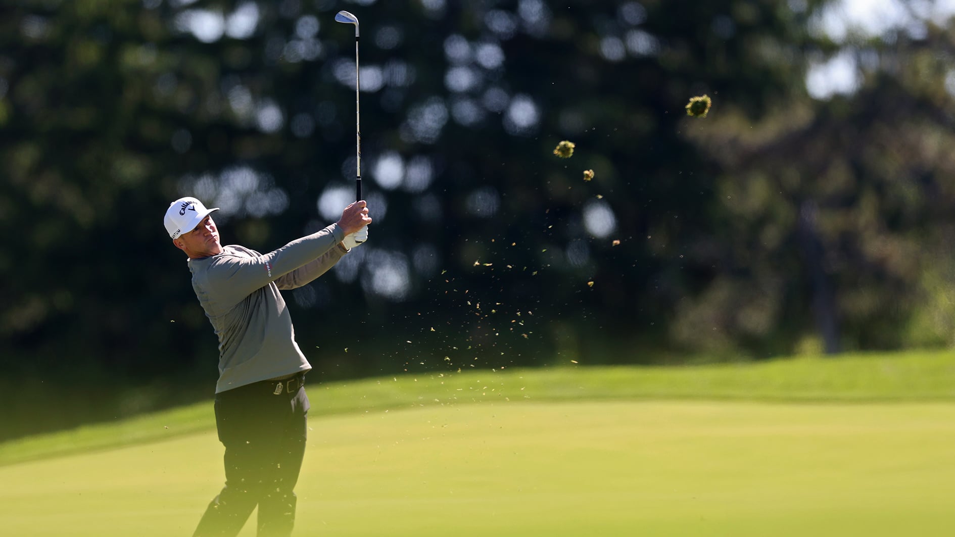 golfspelaren alex norén slår ett golfslag så att gräs yr