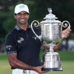 golfspelare med stor pokal på golfbana