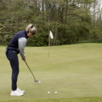 golftränare visar hur man puttar på en golfgreen