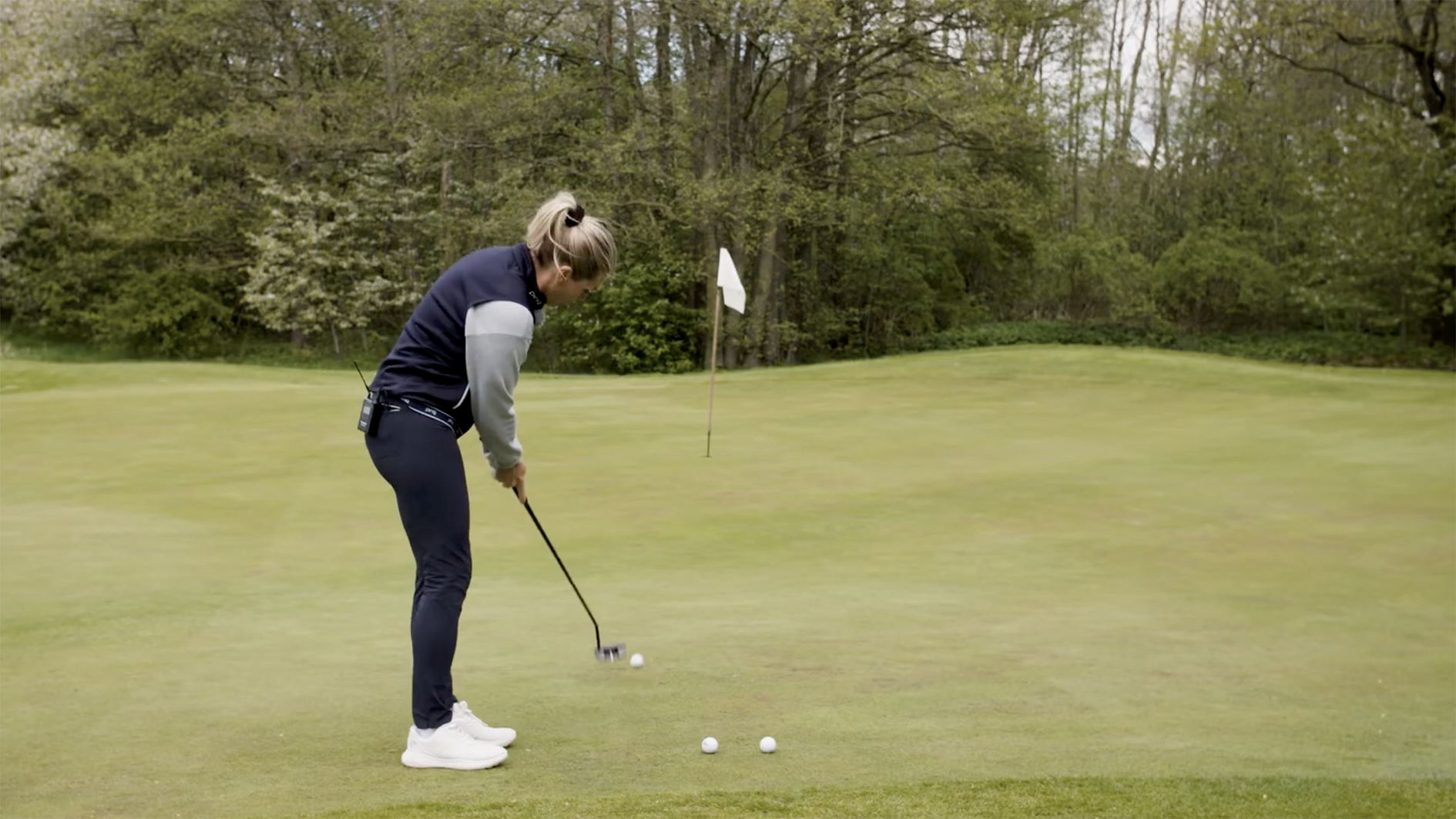 golftränare visar hur man puttar på en golfgreen